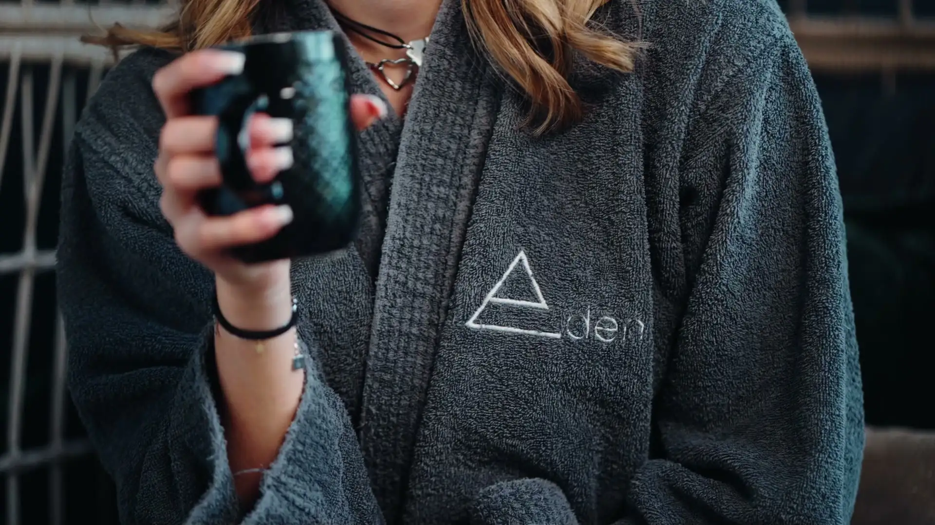 Cliente en peignoir brodé du logo de l'Eden, une tasse à la main