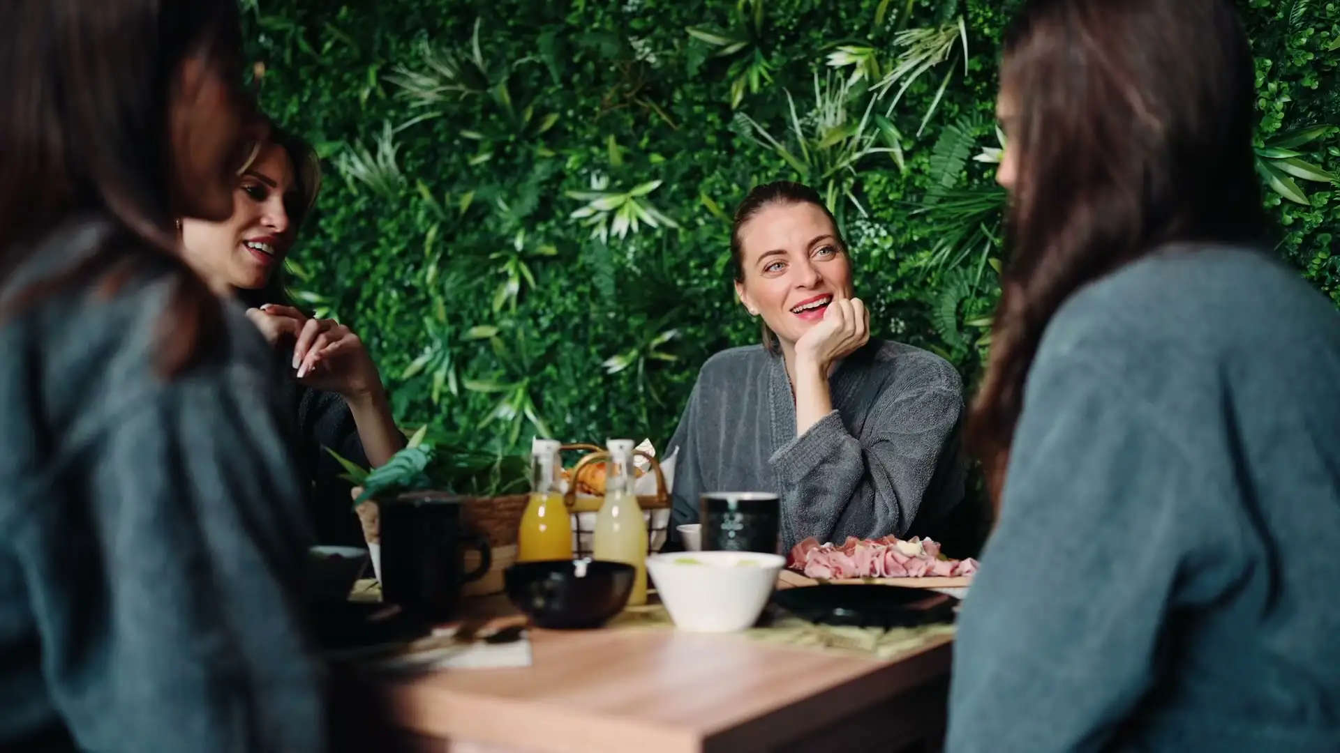 Trois amies partagent un petit déjeuner devant un mur végétal