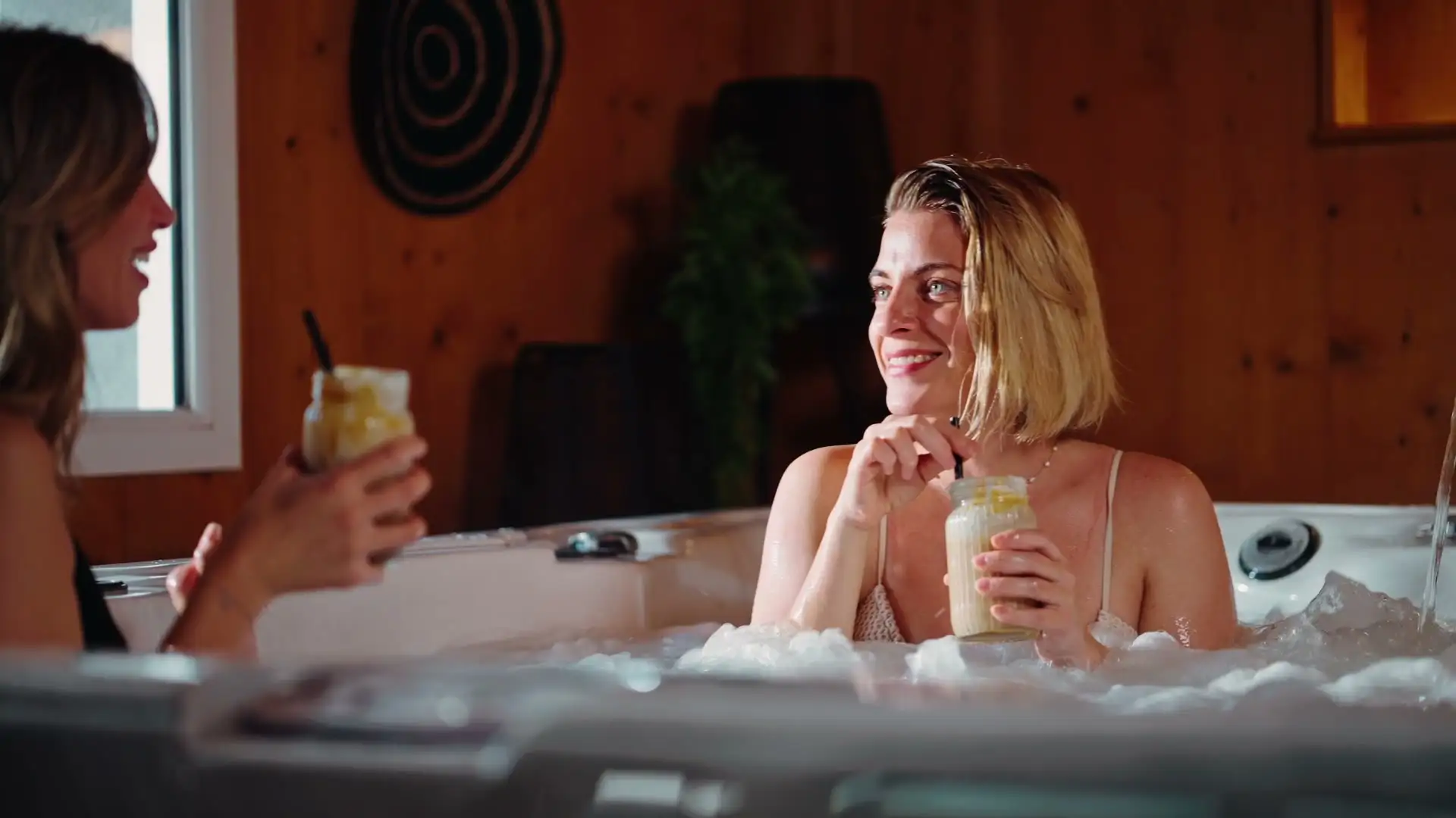 Deux amies prennent un verre dans le spa du Jardin d'Eden, décor de bois clair