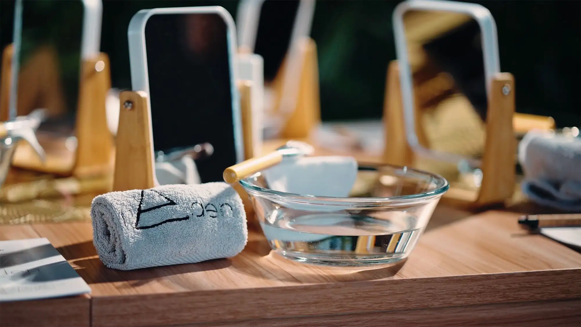 Serviettes brodées du logo de l'Eden, bol et accessoires de soin sur une table en bois