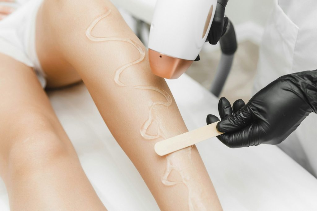 beautician applies gel for laser hair removal on smooth female legs. close-up. laser hair removal