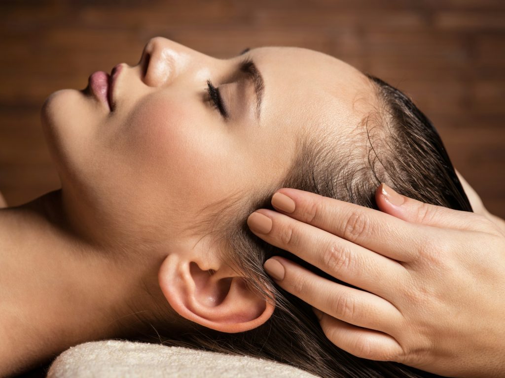 Masseur doing massage the head and hair for an woman in spa salo